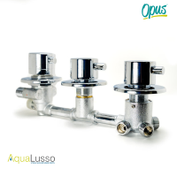 A detailed studio close-up of the Aqualuso Opus Thermostatic Shower Mixer Valve, showing the inlet side of the valve assembly against a clean white background. This image clearly displays the 1/2” BSP threaded inlet connections used for hot and cold water supply, along with the additional inlet used to feed a steam generator where applicable. A high-resolution studio photograph of the Aqualuso Opus Thermostatic Shower Mixer Valve, shown fully assembled with all three chrome control dials installed, positioned horizontally against a clean white background. The image presents the valve as it would appear once fitted behind a shower cabin control panel, making it ideal for homeowners identifying a like-for-like replacement part. The valve consists of three evenly spaced cylindrical control sections connected by a solid metal manifold pipe. Each control is mounted on a circular chrome backplate, giving the valve a clean, symmetrical appearance. The left-hand control represents the selector mechanism used to direct water to the installed shower functions. The central control operates the flow and on/off function, while the right-hand control houses the thermostatic cartridge responsible for regulating and maintaining a stable water temperature. Below the control assembly, the chrome-plated valve body transitions into a textured metal housing where the threaded connection ports are visible. These 1/2” BSP threaded connections are designed for compatibility with Aqualuso Opus shower cabins and steam showers, allowing the valve to be replaced without modifying existing pipework. The image clearly shows the compact layout and fixed spacing between controls, confirming the 100mm centre-to-centre measurements used across the Opus range. Branding elements are visible within the image, including the Aqualusso logo in the lower corner and the Opus mark in the upper corner, reinforcing that this valve is part of the Opus system. This visual helps customers confidently identify the correct replacement mixer valve when their existing Aqualuso Opus shower valve has failed, seized, or no longer operates correctly.